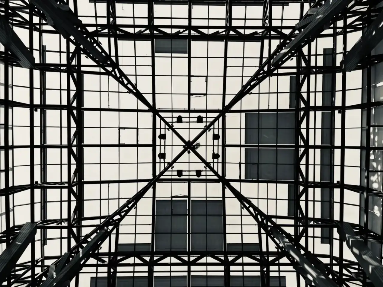 Zicht recht omhoog door een stalen dakconstructie met glas boven een atrium